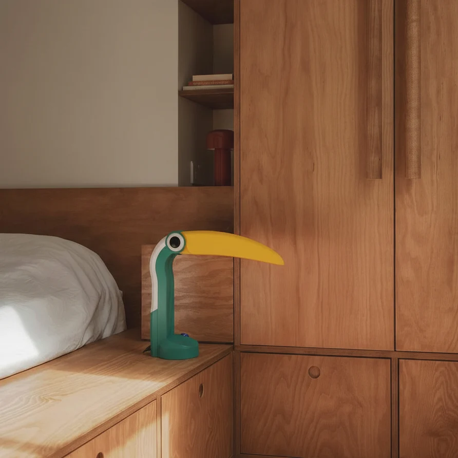 Green and yellow Toucan Lamp on a wooden bedside shelf